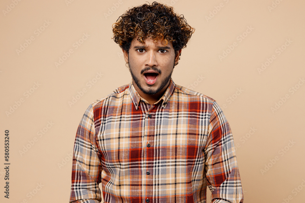 Sad Indian man wear brown shirt casual clothes look camera with opened mouth pov displeased facial expression isolated on plain pastel light beige background studio portrait. People lifestyle concept. Sad Indian man wear brown shirt casual clothes look camera with opened mouth pov displeased facial expression isolated on plain pastel light beige background studio portrait. People lifestyle concept.