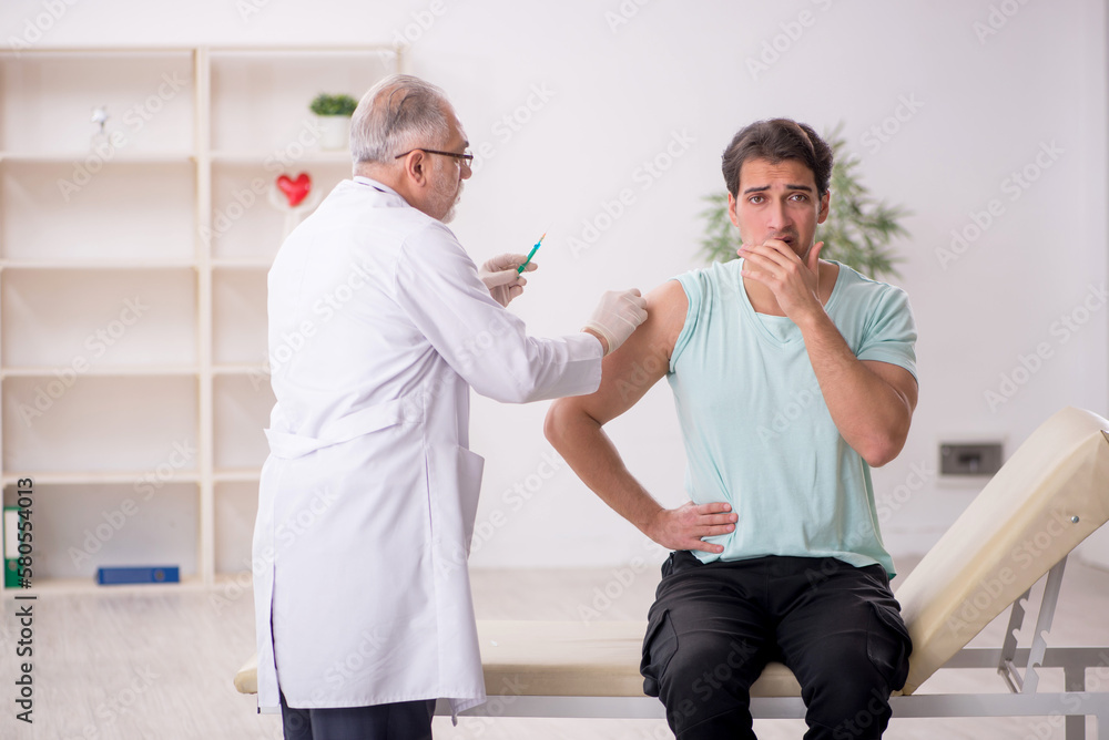Fototapeta premium Young male patient visiting old male doctor in vaccination conce