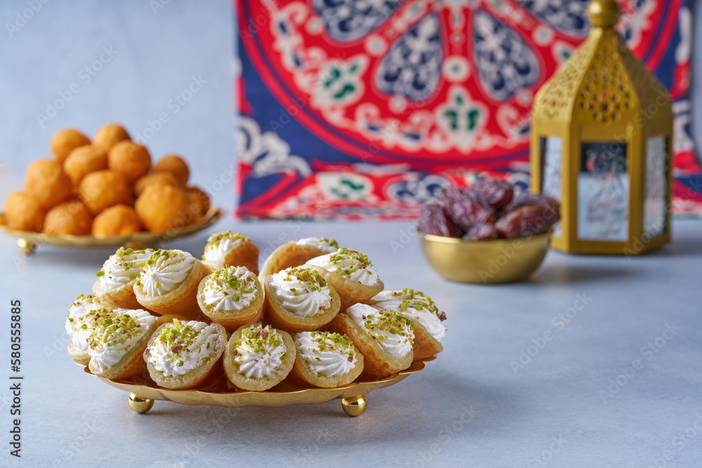 Arabian pancake Qatayef with qishta cream and pistachio . Traditional sweets with ramadan decor .