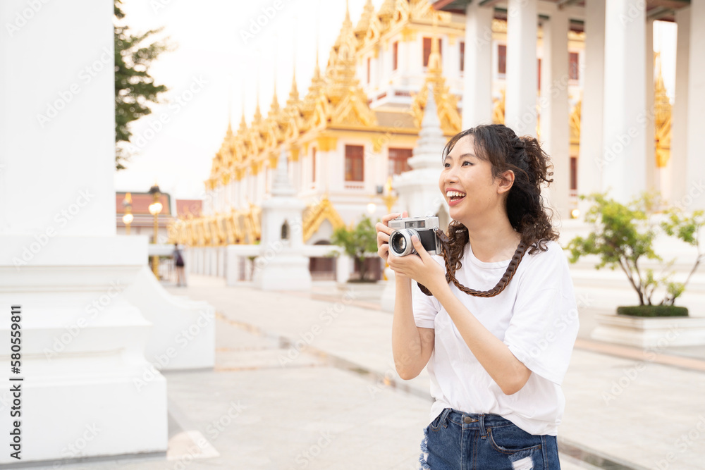 Asian woman tourist backpacker smiling, traveling and taking photo with temple background in Bangkok, Thailand. Asian people excited and having fun traveling.
