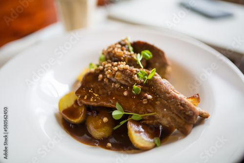 Gourmet veal cheek dish with fresh beef sauce and small potatoes garnished with greens in fancy gourmet restaurant
