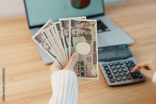 Woman hand counting Japanese Yen banknote with calculator. Thousand Yen money. Japan cash, Tax, Recession Economy, Inflation, Investment, finance, salary and payment concepts