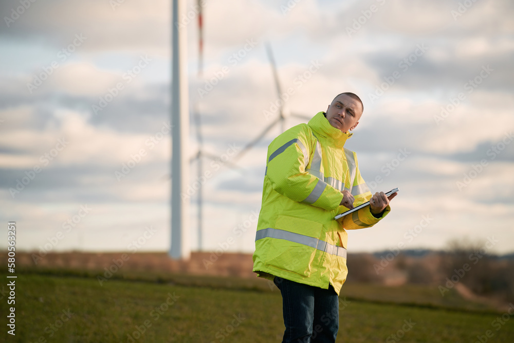 Naklejka premium engineer man stands in a wind turbine field.