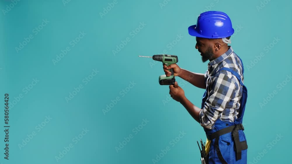 Male builder using power drill instrument on wall, drilling nails with cordless machine tool on camera. Professional mechanic with hardhat holding nail gun to drill holes, building machinery. Male builder using power drill instrument on wall, drilling nails with cordless machine tool on camera. Professional mechanic with hardhat holding nail gun to drill holes, building machinery.