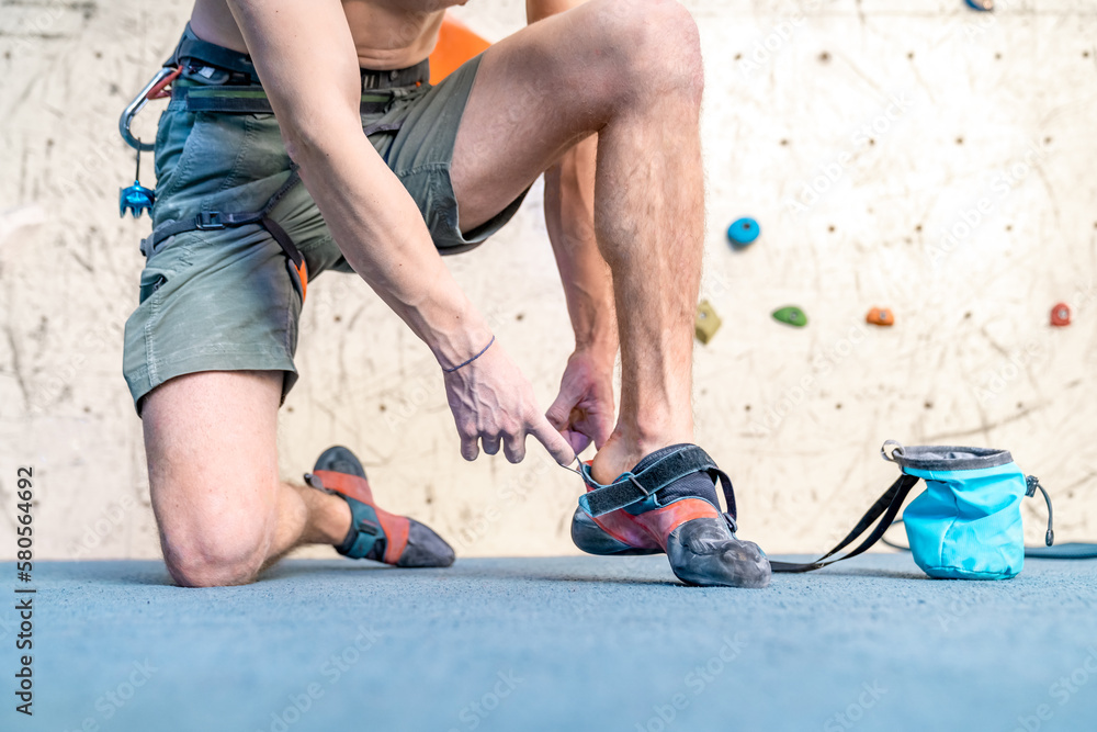 putting on climbing shoes next to the climbing wall