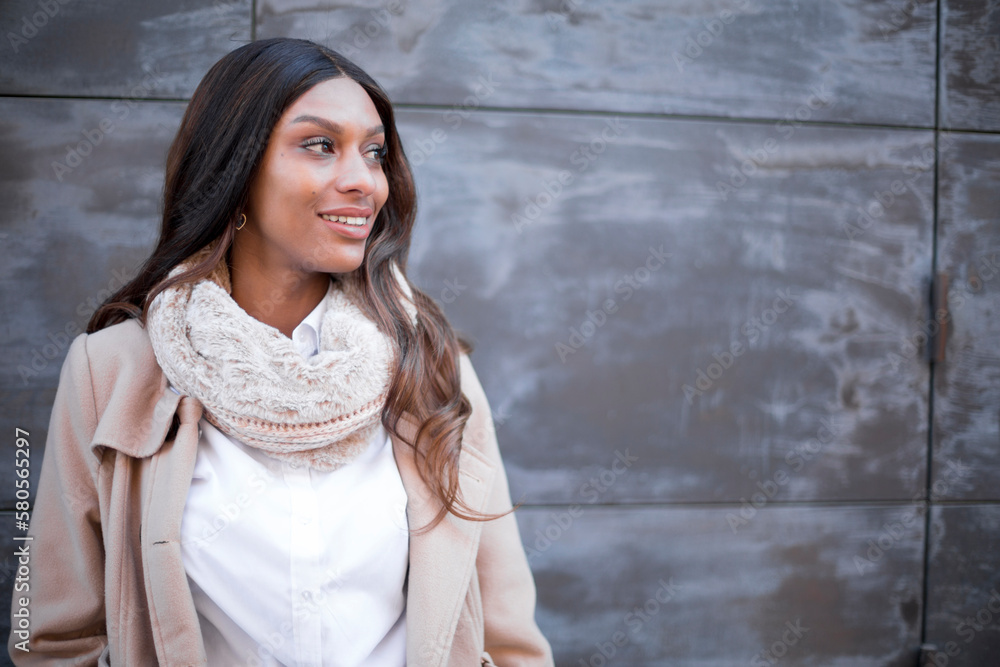 Fototapeta premium Distracted african woman smiling in front of an urban wall