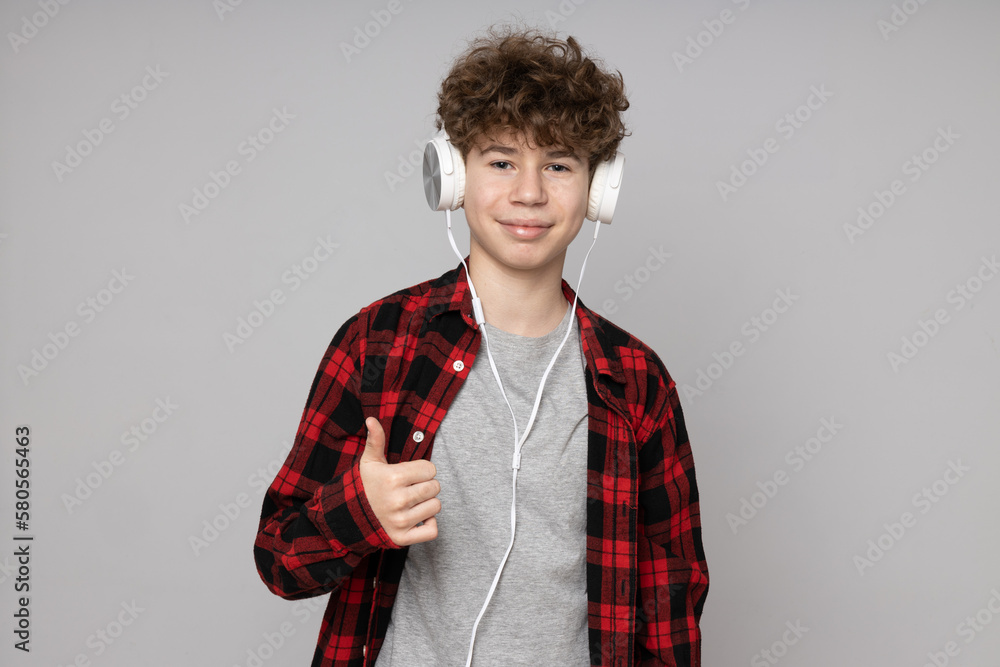 Obraz premium Attractive boy, teenager in headphones on gray background