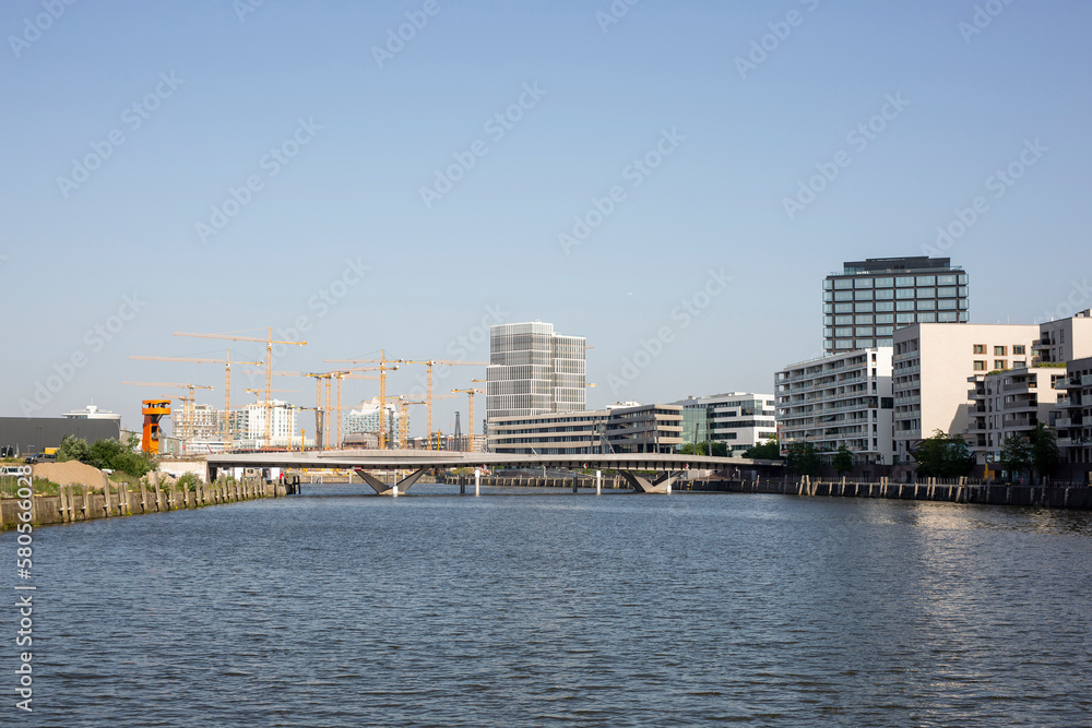 Germany, Hamburg, Elbe river flowing through HafenCity with bridge and large construction site in background Germany, Hamburg, Elbe river flowing through HafenCity with bridge and large construction site in background