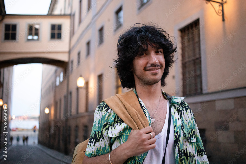 Smiling young man carrying jacket walking in alley Smiling young man carrying jacket walking in alley