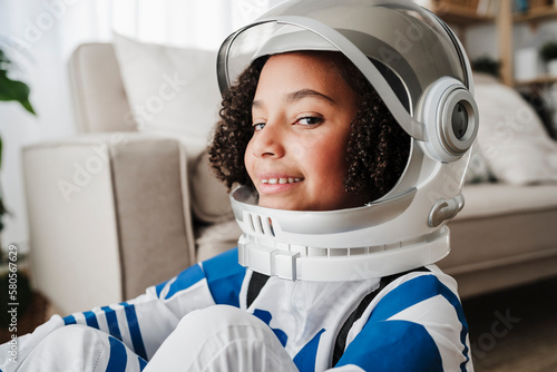 Smiling girl wearing space helmet at home photo