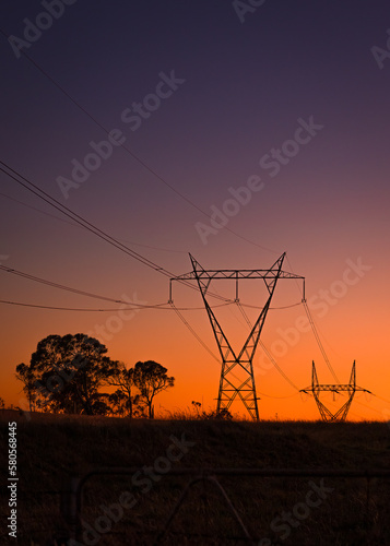 Obraz na plátně Silhouetted power line pylons against a sunset sky