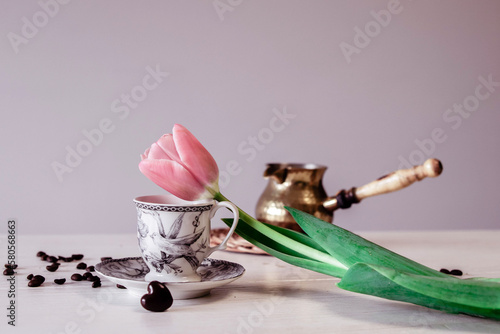 Spring tulip flower, coffee cup on a wooden white table. Pot of coffee, coffee beans 