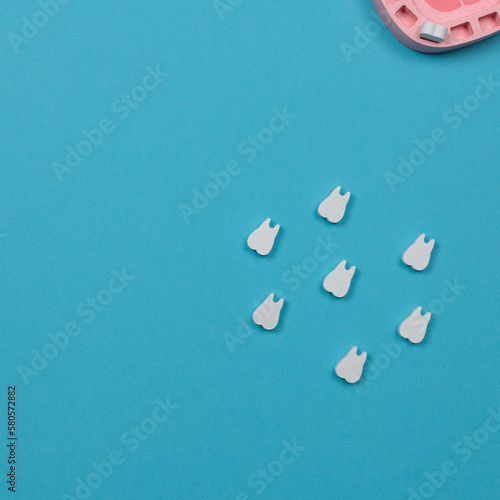 Toy wooden teeth on a blue background, top view, copy space.