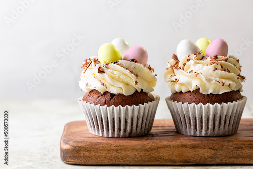 Photography Easter chocolate cupcakes with cream cheese, sweet candy eggs and nest