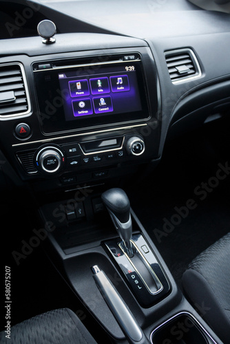 Modern car panel interior with close-up details of multimedia system, air conditioning control panel and automatic transmission with handbrabrake