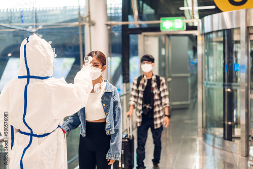 Doctor woman use infrared forehead thermometer for checking body temperature scan travel passenger fever in quarantine for coronavirus wearing safety protective mask at International terminal airport