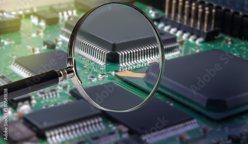 view of printed circuit board with active and passive surface mounted components close up through magnifying glass photo