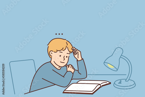 Boy child sit at desk reading book 