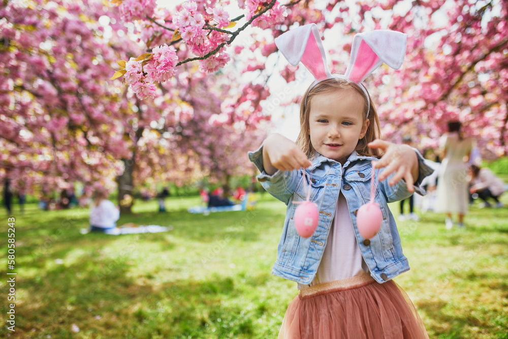 Preschooler girl wearing bunny ears playing egg hunt on Easter Preschooler girl wearing bunny ears playing egg hunt on Easter