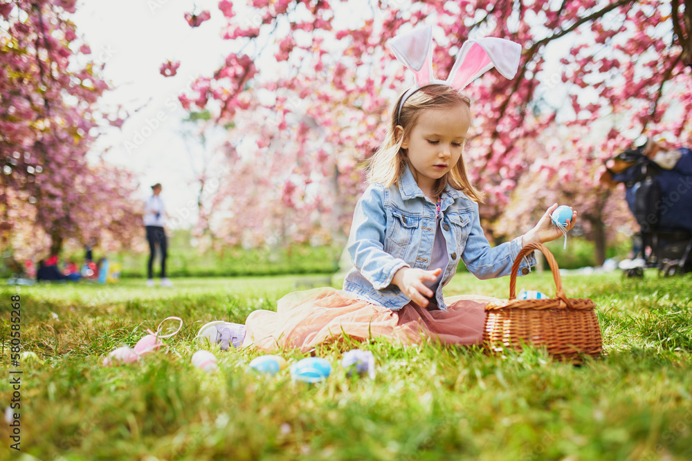 Preschooler girl wearing bunny ears playing egg hunt on Easter Preschooler girl wearing bunny ears playing egg hunt on Easter