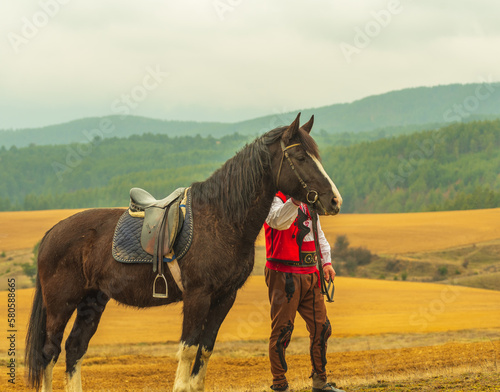 People in traditional bulgarian clothing riding a horse in the mountains