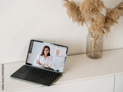 Video interview. Web chat. Online communication. Confident business woman on laptop screen at home interior digital office with free space. photo