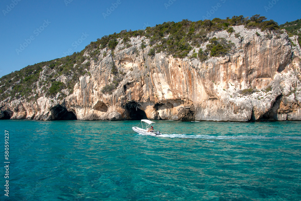 Fototapeta premium Mare blu e le caratteristiche grotte naturali di Cala Luna, Dorgali, Golfo di Orosei, Sardegna, Italia. Grandi grotte marine nella costa mediterranea. Sardegna, Italia.