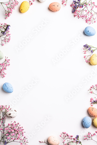 Photography Overhead shot of Easter composition with spring flowers and colorful quail eggs over white background