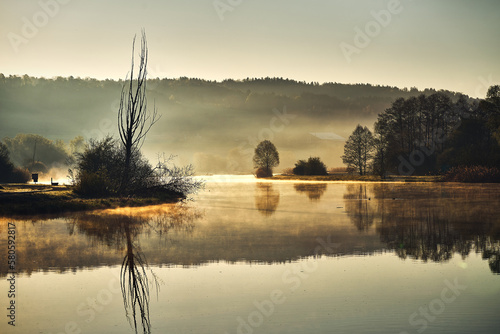 Schöner Sonnenaufgang im Natuschutzgebiet Flachsee (Reuss) bei Rottenschwil. Die Silhouetten spiegeln sich in der glatten Wasseroberfläche. photo