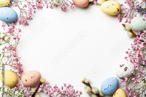 Canvas Print Overhead shot of Easter composition with spring flowers and colorful quail eggs over white background