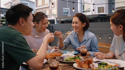 Mom enjoy thai meal cooking for family day meet talk home dining at dine table cozy patio. Group asia people young adult man woman friend fun joy relax warm night time picnic eat yummy food with mum.