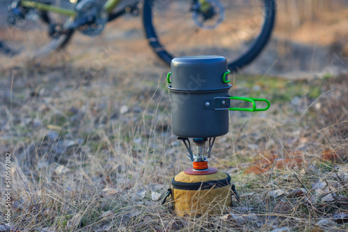 Camping in the open air, on the background of a bicycle and a forest. Tourist gas burner with pans for cooking.
