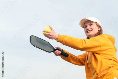 portrait woman player pickleball game over blue sky, pickleball yellow ball with paddle, outdoor sport leisure activity