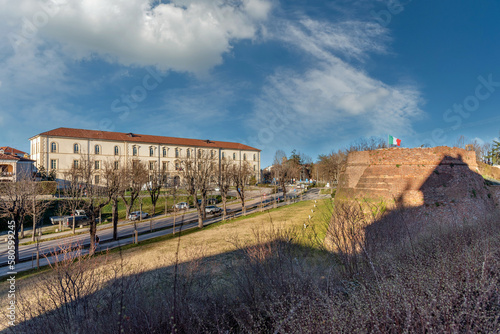 Fossano, Cuneo, Italy - 11 March 2023: primary school and scientific high school in building of the former Eusebio Bava Barracks with tree-lined avenue Salice slope and ancient bastion of Porta Salice