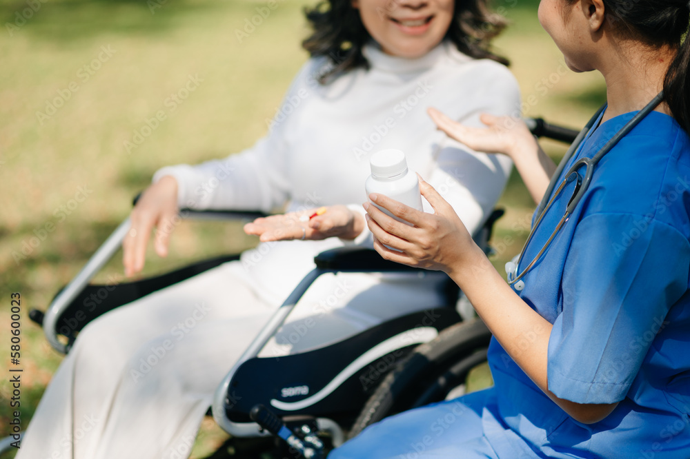 Elderly asian senior woman on wheelchair with Asian careful caregiver and encourage patient, walking in garden. with care from a caregiver and senior health insurance.. Elderly asian senior woman on wheelchair with Asian careful caregiver and encourage patient, walking in garden. with care from a caregiver and senior health insurance..