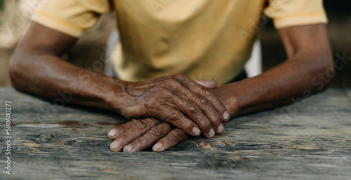 Close up of male wrinkled hands, old man is wearing on the wood table
