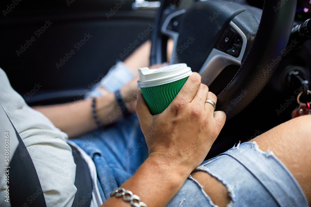 Joyful man driving car while drinking coffee on trip