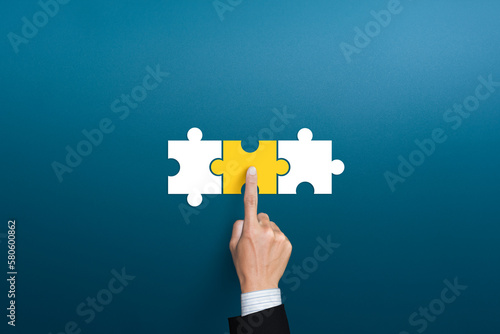 Businessman hand connecting yellow puzzle pieces. joint venture, partnership, Mergers or acquisition concept