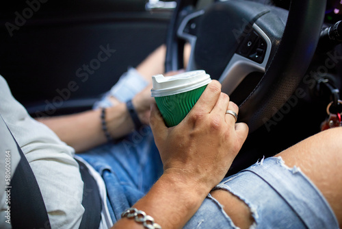 Joyful man driving car while drinking coffee on trip