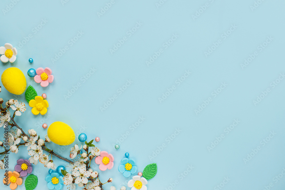 Happy Easter! Easter eggs, candy flowers and blooming cherry branch  flat lay on blue background. Stylish easter template with space for text. Greeting card or banner
