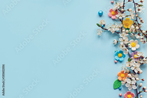 Stylish colorful candy flowers and cherry blossoms flat lay on blue background with copy space. Happy Easter! Greeting card template or modern holiday banner. Happy Mothers day © sonyachny