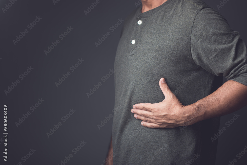 Man is using his hand to cover over left side of stomach because of