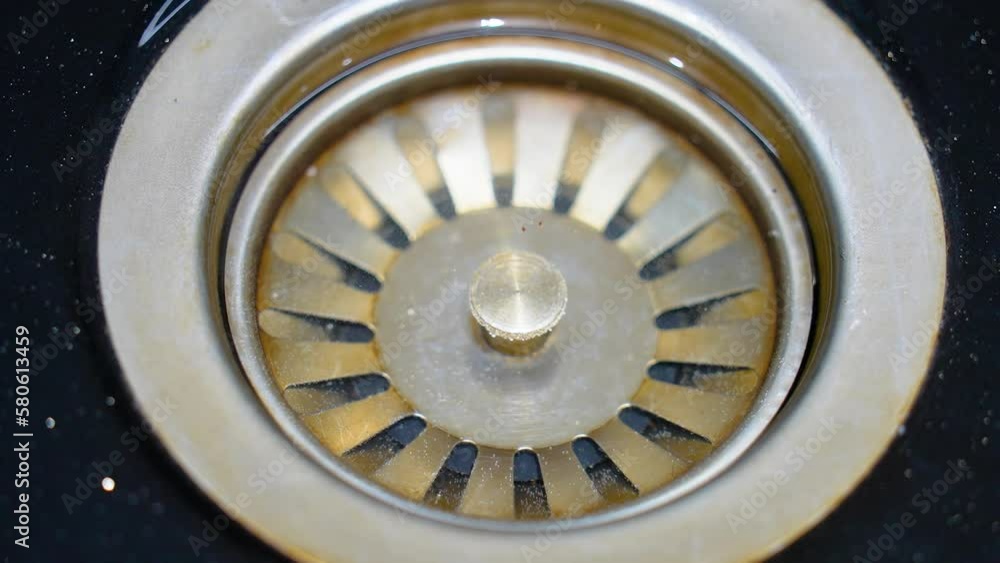 Sink in the kitchen. Concept: saving water, lack of resources, irrational use of water, drinking water from a tap. Water flows into the drain hole in the metal sink. Sink in the kitchen. Concept: saving water, lack of resources, irrational use of water, drinking water from a tap. Water flows into the drain hole in the metal sink.