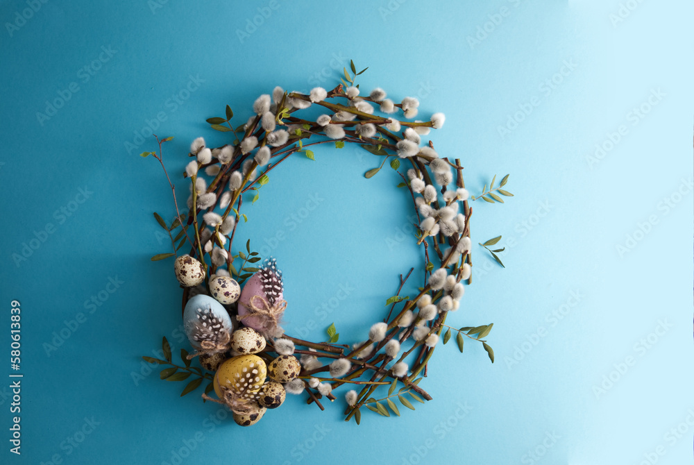 Naklejka premium Spring willow wreath decorated with easter eggs and quail eggs on a blue background copy space