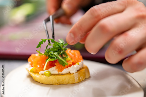 man chef hand cooking Bruschetta with salmon and cream cheese on restaurant kitchen