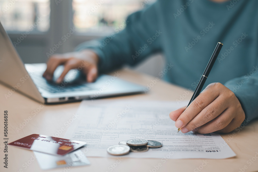 US IRS 1040 form or US Individual income tax Concept,accountant holding pen working on calculator business with data accounting documents and a laptop, pay tax in 2023 years,new year 2023 tax concept US IRS 1040 form or US Individual income tax Concept,accountant holding pen working on calculator business with data accounting documents and a laptop, pay tax in 2023 years,new year 2023 tax concept