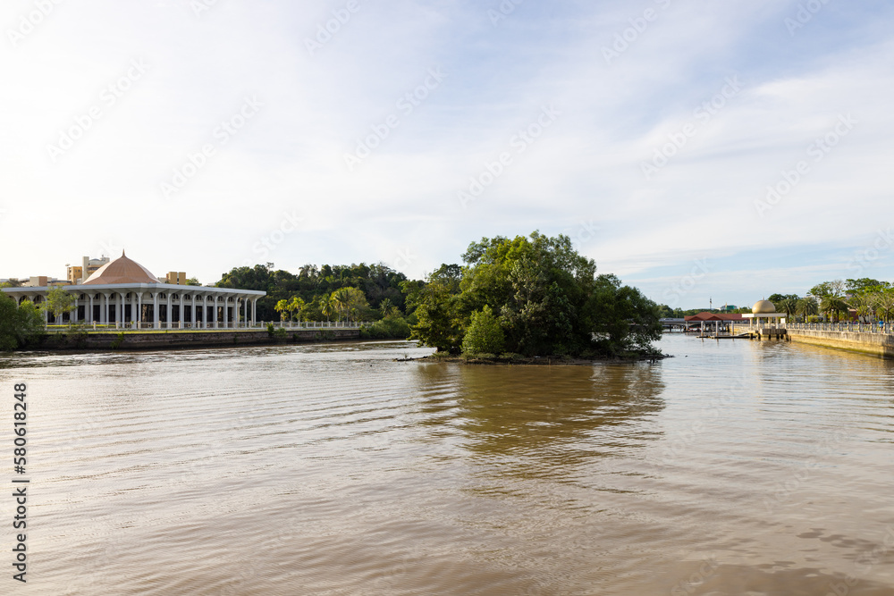 trees, boat and building along Sungai Kedayan river, the capital of Brunei Darussalam in sunny day with white coulds and blue sky trees, boat and building along Sungai Kedayan river, the capital of Brunei Darussalam in sunny day with white coulds and blue sky