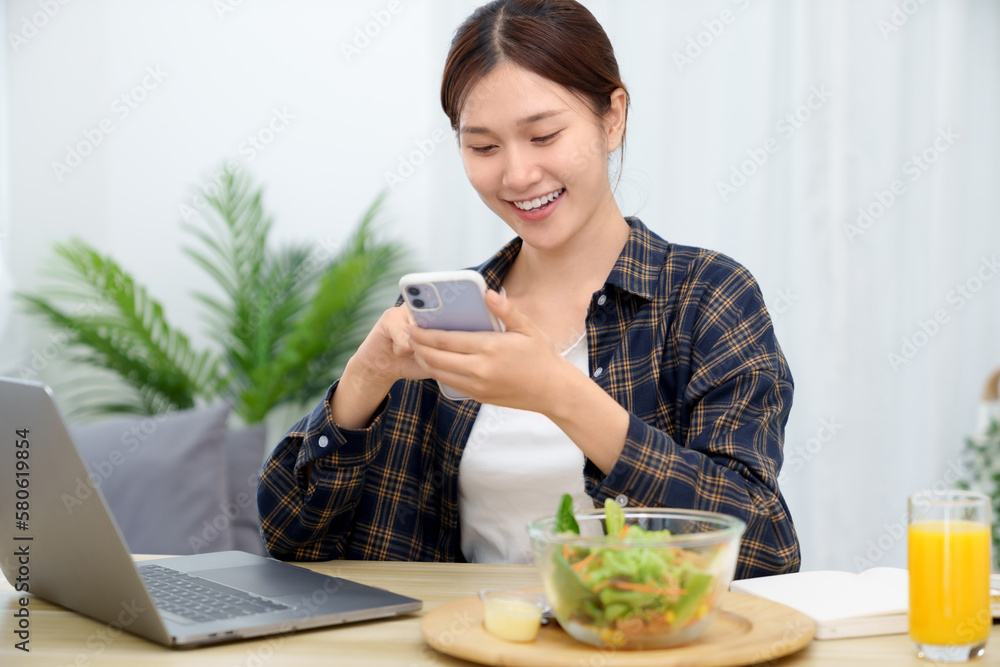 Asian businesswoman having lunch break and  typing on the laptop. working at home concept