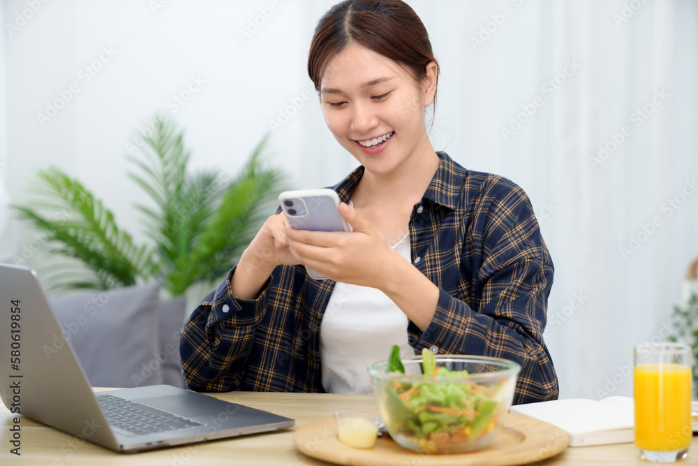 Asian businesswoman having lunch break and typing on the laptop. working at home concept Asian businesswoman having lunch break and typing on the laptop. working at home concept