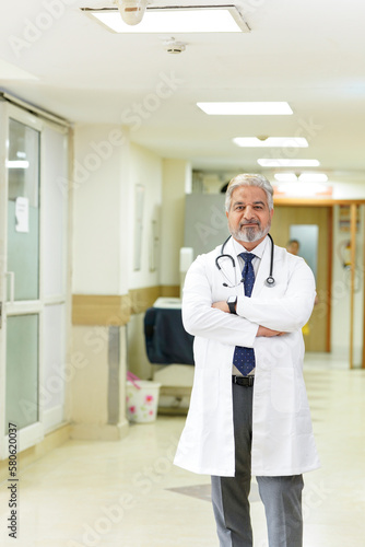 Indian male senior doctor standing at hospital.